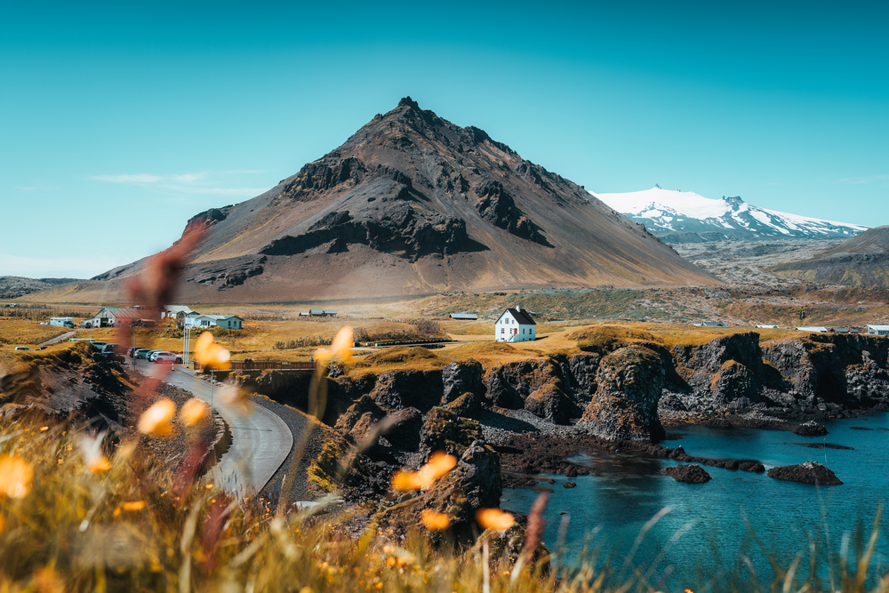 Фото гарний вид на рибальське село Арнарстапі з нордичними будинками та гору вулкану Стапафелль біля базальтових скель на узбережжі півострова Снефельснес в Ісландії