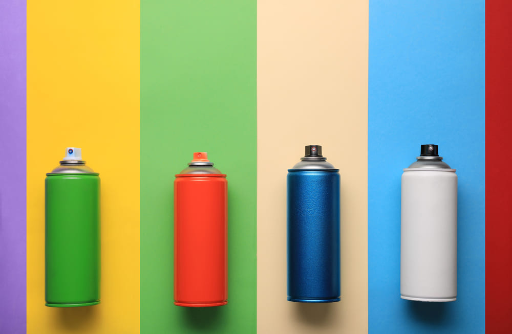 Cans of different spray paints on color background, flat lay with space for text. Graffiti supplies — Photo
